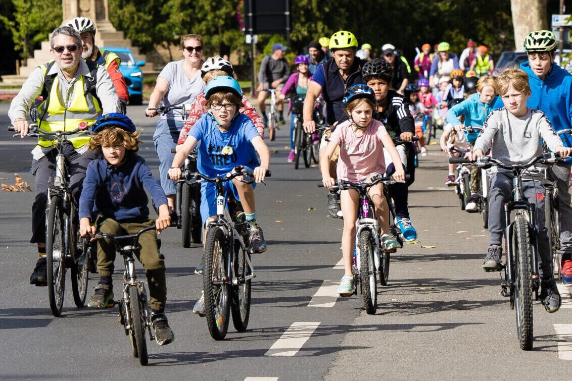 Procession of children cycling from the Plain towards Magdalen Bridge in Oxford. They are flanked by marshals, also on bikes and wearing hi-vis jackets