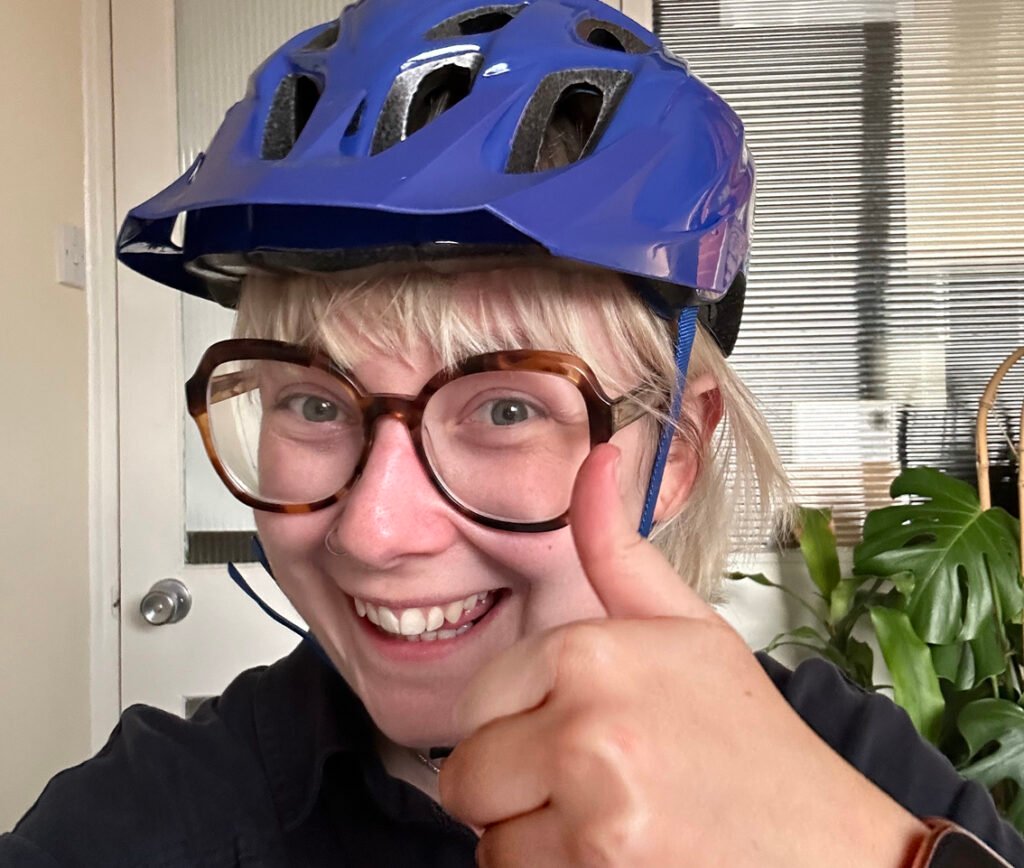 Young white woman in cycle helmet giving thumbs up