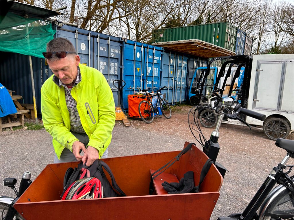 White man in cycle gear, in cycle depot loading cargo bike