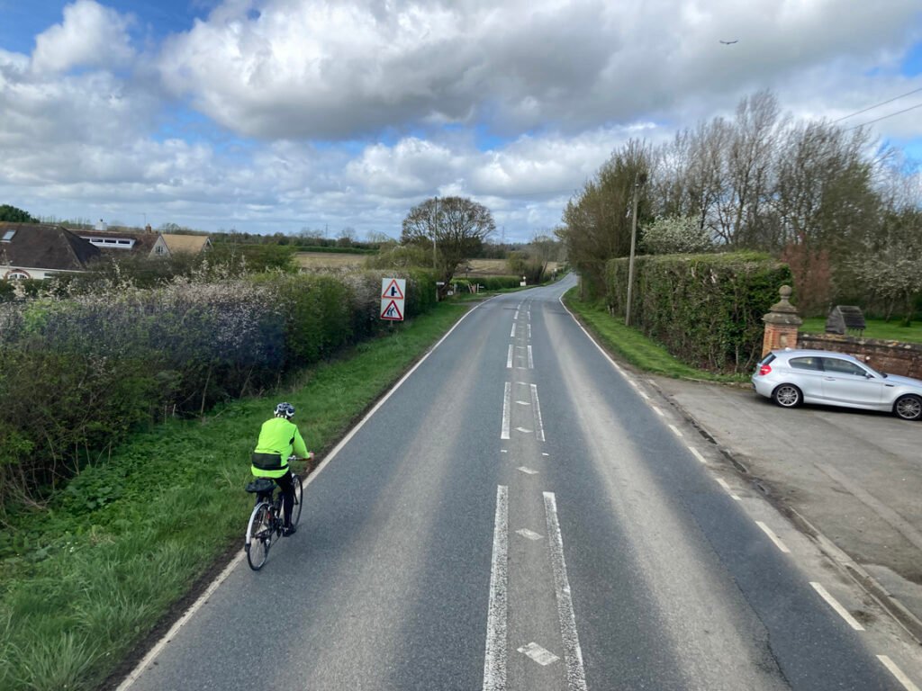 Empty road in countryside with cyclist in hi-vis jacket